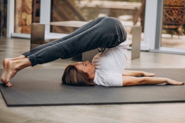 Evde yoga yapan genç bir kadın.