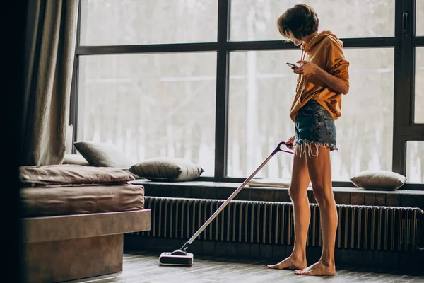 Woman vacuuming at home and dancing