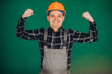 Yeşil arka planda izole edilmiş kasketli işçi.