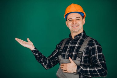 Yeşil arka planda izole edilmiş kasketli işçi.