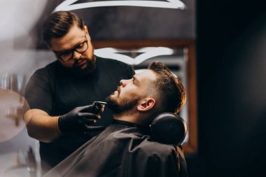 Berber dükkanında sakal kesen yakışıklı adam.