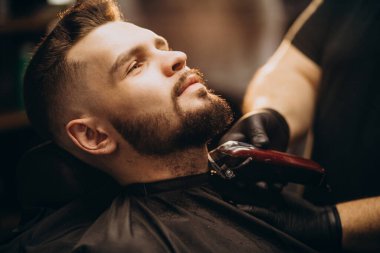 Berber dükkanında sakal kesen yakışıklı adam.
