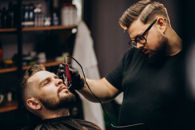 Berber dükkanında sakal kesen yakışıklı adam.