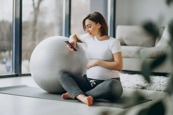Young Pregnant Woman Practicing Yoga Home Using Phone — Stock fotografie