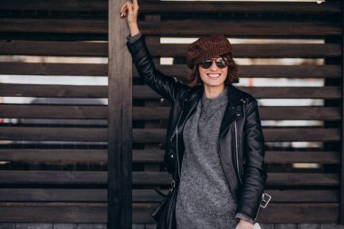 Caddenin dışında deri ceketli güzel bir kadın var.