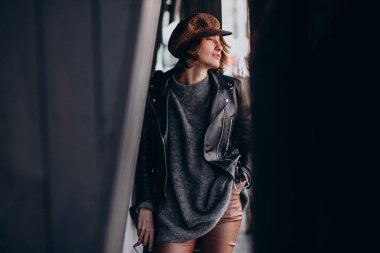 Caddenin dışında deri ceketli güzel bir kadın var.