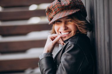 Caddenin dışında deri ceketli güzel bir kadın var.