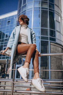 İş merkezinin yanındaki günlük kıyafetli genç iş kadını.