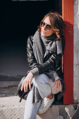 Caddenin dışında deri ceketli genç bir kadın.