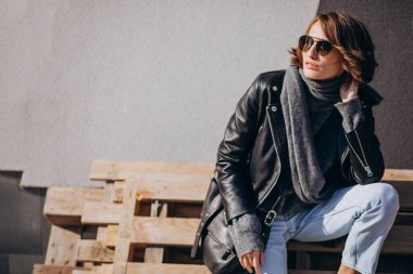 Caddenin dışında deri ceketli genç bir kadın.
