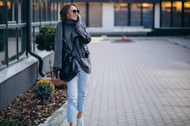 Caddenin dışında deri ceketli genç bir kadın.