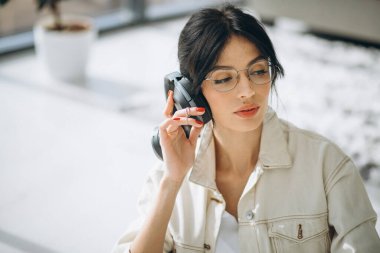 Genç, güzel bir kadın, kablosuz kulaklıkla müzik dinliyor.