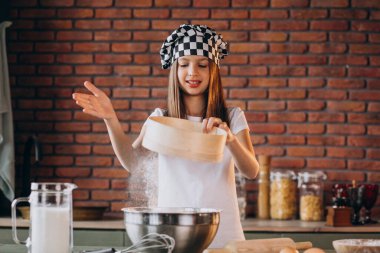 Küçük kız kahvaltı için mutfakta hamur işi pişiriyor.