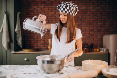 Küçük kız kahvaltı için mutfakta hamur işi pişiriyor.
