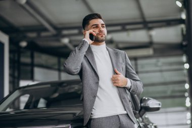 Araba galerisinde telefonda konuşan yakışıklı bir iş adamı.
