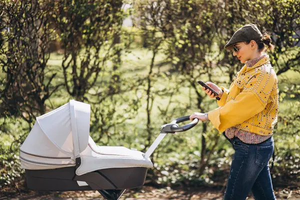 Молода Мати Ходить Дитячим Перевезенням Парку Використовує Телефон — стокове фото