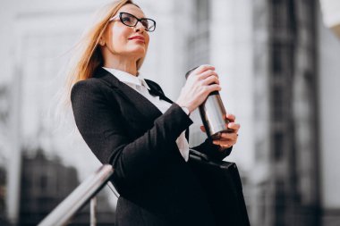 Çekici bir iş kadını dışarıda kahve içiyor.