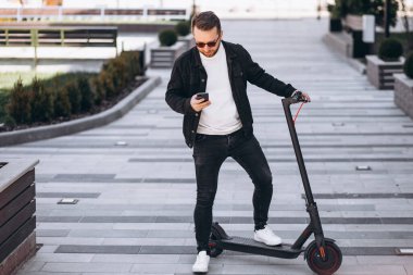 Scooter kullanan yakışıklı adam telefonda internetten alışveriş yapıyor.