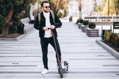 Parkta scooter süren yakışıklı bir genç.