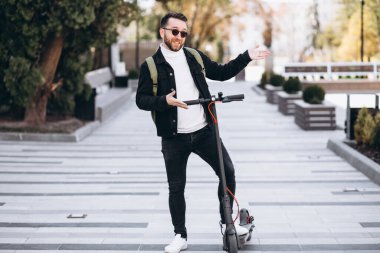 Parkta scooter süren yakışıklı bir genç.