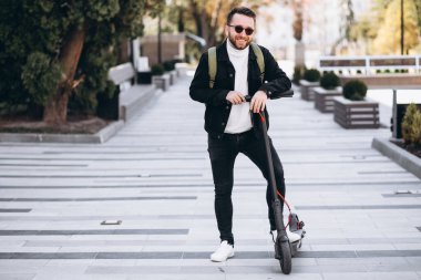 Parkta scooter süren yakışıklı bir genç.