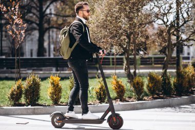 Parkta scooter süren yakışıklı bir genç.