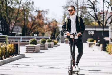 Parkta scooter süren yakışıklı bir genç.
