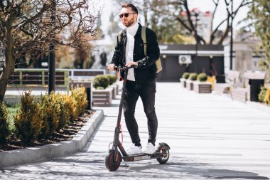 Parkta scooter süren yakışıklı bir genç.