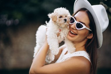 Güzel bir kadın küçük köpeğini tutuyor.