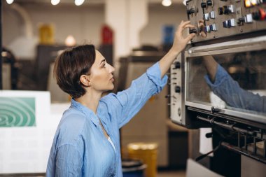 Matbaada çalışan kağıt ve boyalarla çalışan bir kadın.
