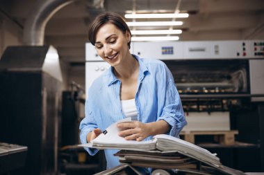 Matbaada çalışan kağıt ve boyalarla çalışan bir kadın.