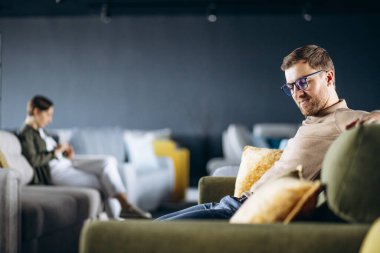 Çift mobilya dükkanında kanepe ve yastık seçiyor.