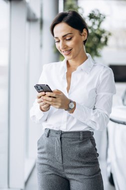 Vitrindeki telefonu kullanan bir iş kadını.