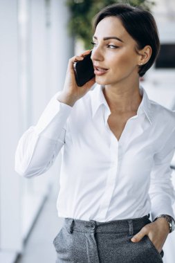 Vitrindeki telefonu kullanan bir iş kadını.
