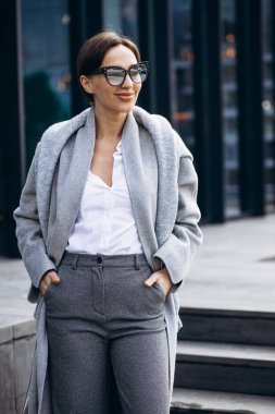 Gri ceketli güzel iş kadını ofis binasının dışında.