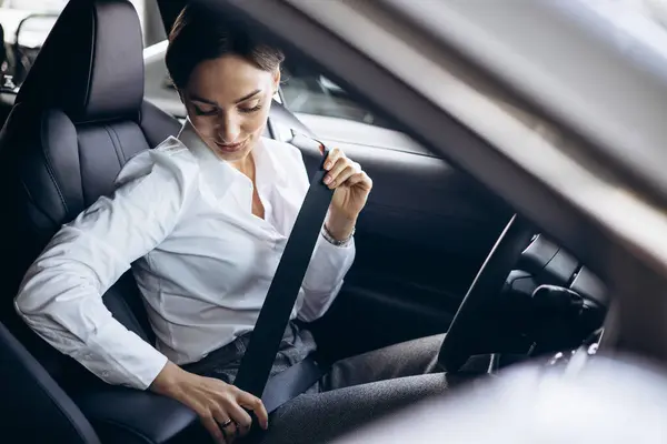 Woman fastening safety belt in car