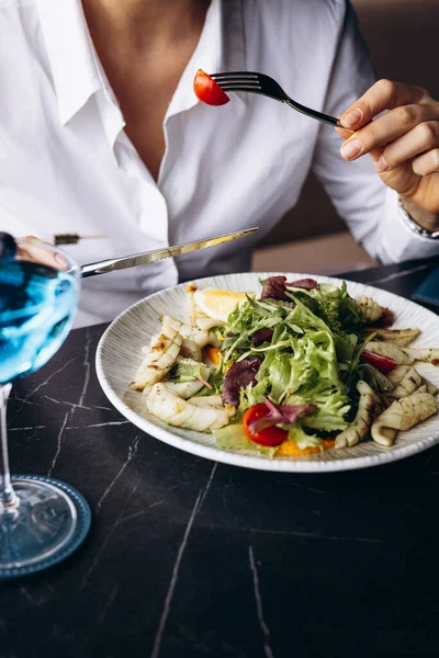 Kokteyl içip kafede salata yiyen bir kadın.