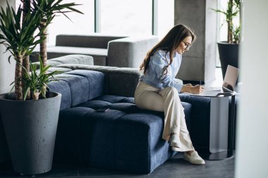 Serin ofis bölgesinde dizüstü bilgisayarda çalışan genç iş kadını.