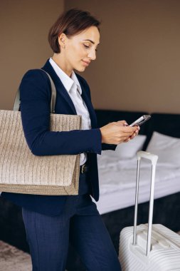 Otel odasında konuşan ve bavullarını taşıyan bir iş kadını.