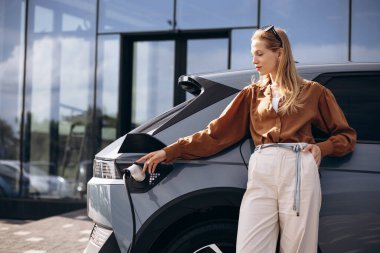 İş kadını elektrikli arabayı şarj ediyor