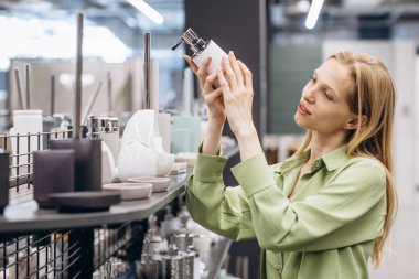 İç pazarda banyo için sabun şişesi seçen bir kadın.