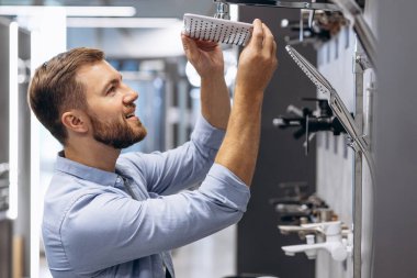 İnşaat pazarındaki adam banyosu için duşu seçiyor.