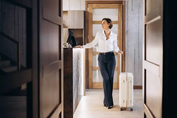 Business woman with luggage at the hotel reception
