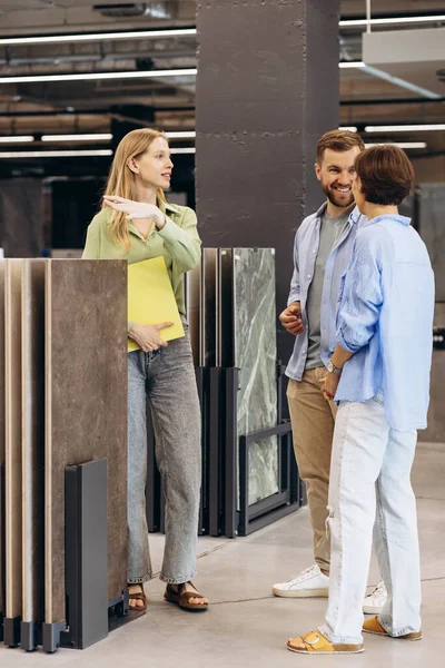 Couple talking to sales woman at building market choosing tile for their home