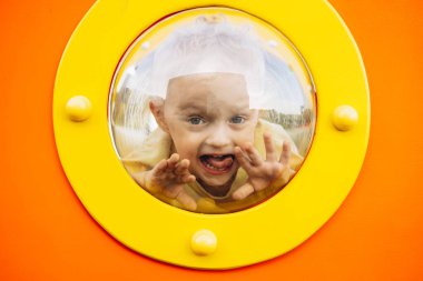 Küçük çocuk oyun parkının penceresinden bakıyor.