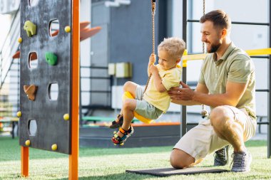 Baba oğul oyun alanında oynuyorlar.