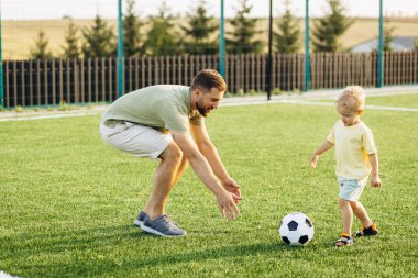 Baba oğul futbol sahasında oynuyorlar.
