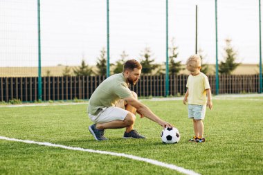 Baba oğul futbol sahasında oynuyorlar.