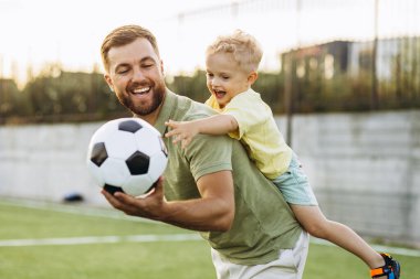 Baba oğul futbol sahasında oynuyorlar.