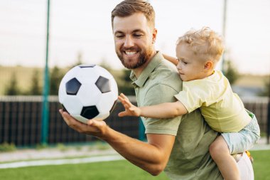 Baba oğul futbol sahasında oynuyorlar.